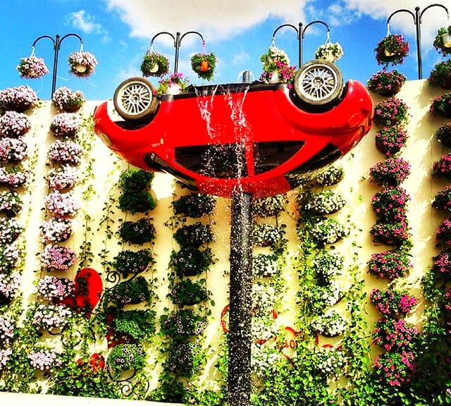 An Upside-down version of inverted Volkswagen Car with a waterfall at the Dubai Miracle Garden.