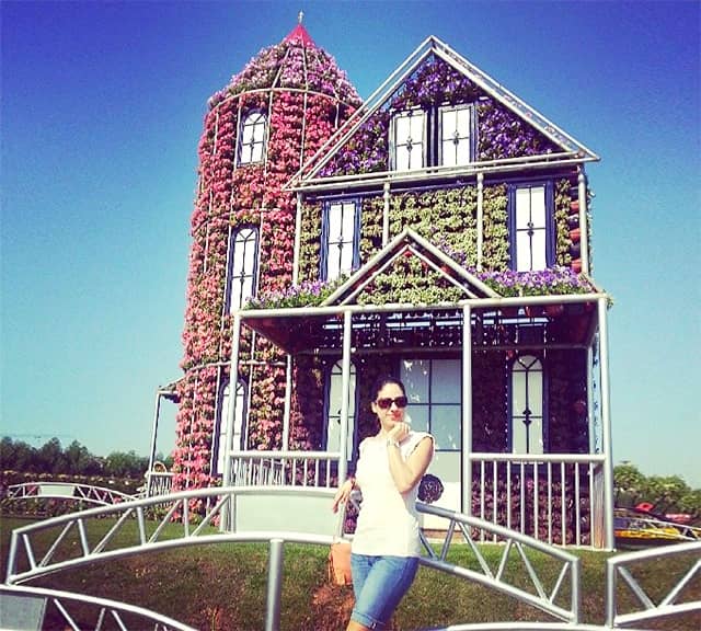 Photograph of a visitor with a Floral House at the Dubai Miracle Garden.